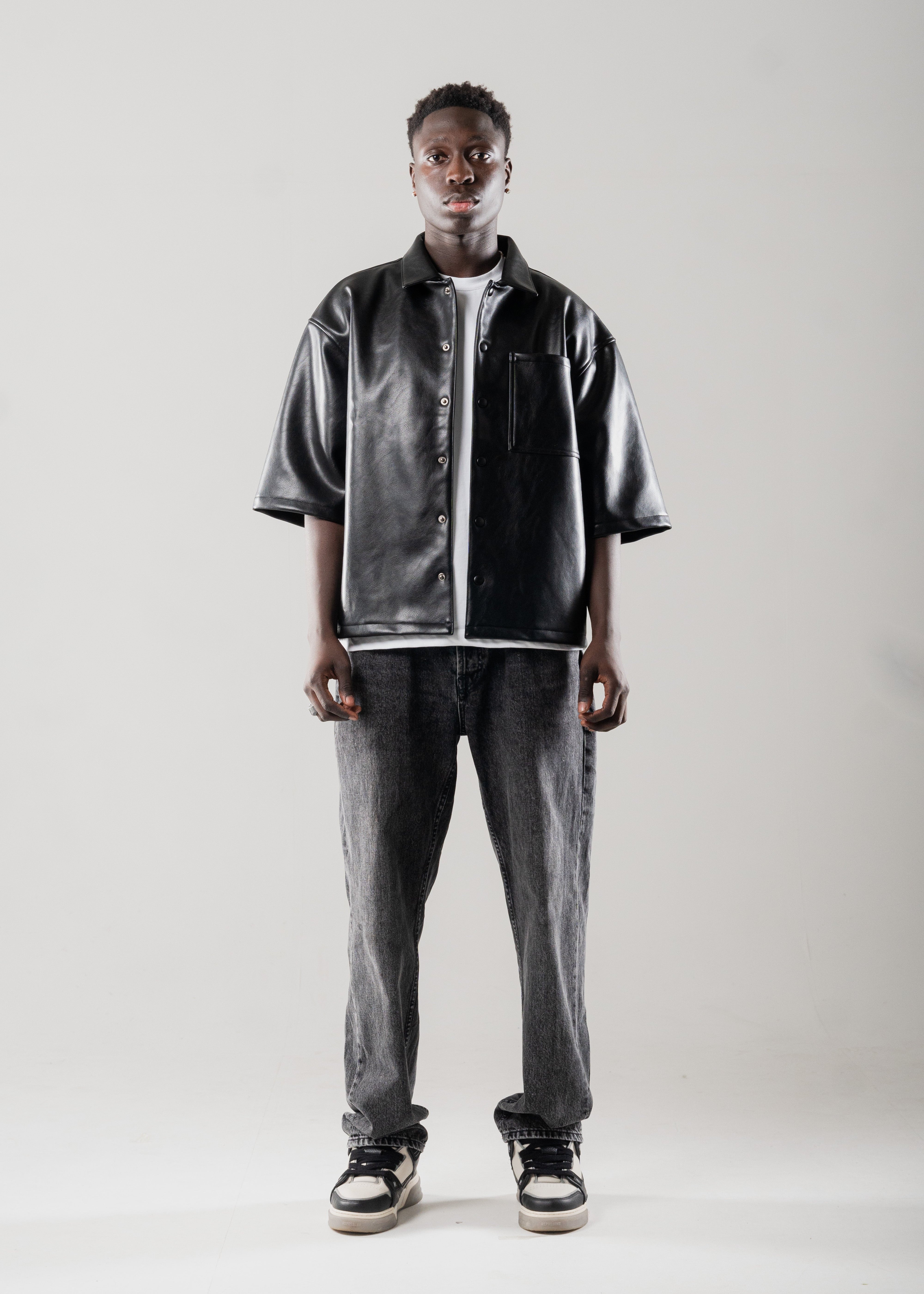 Model styled in Mallacco black vegan leather shirt with straight trousers