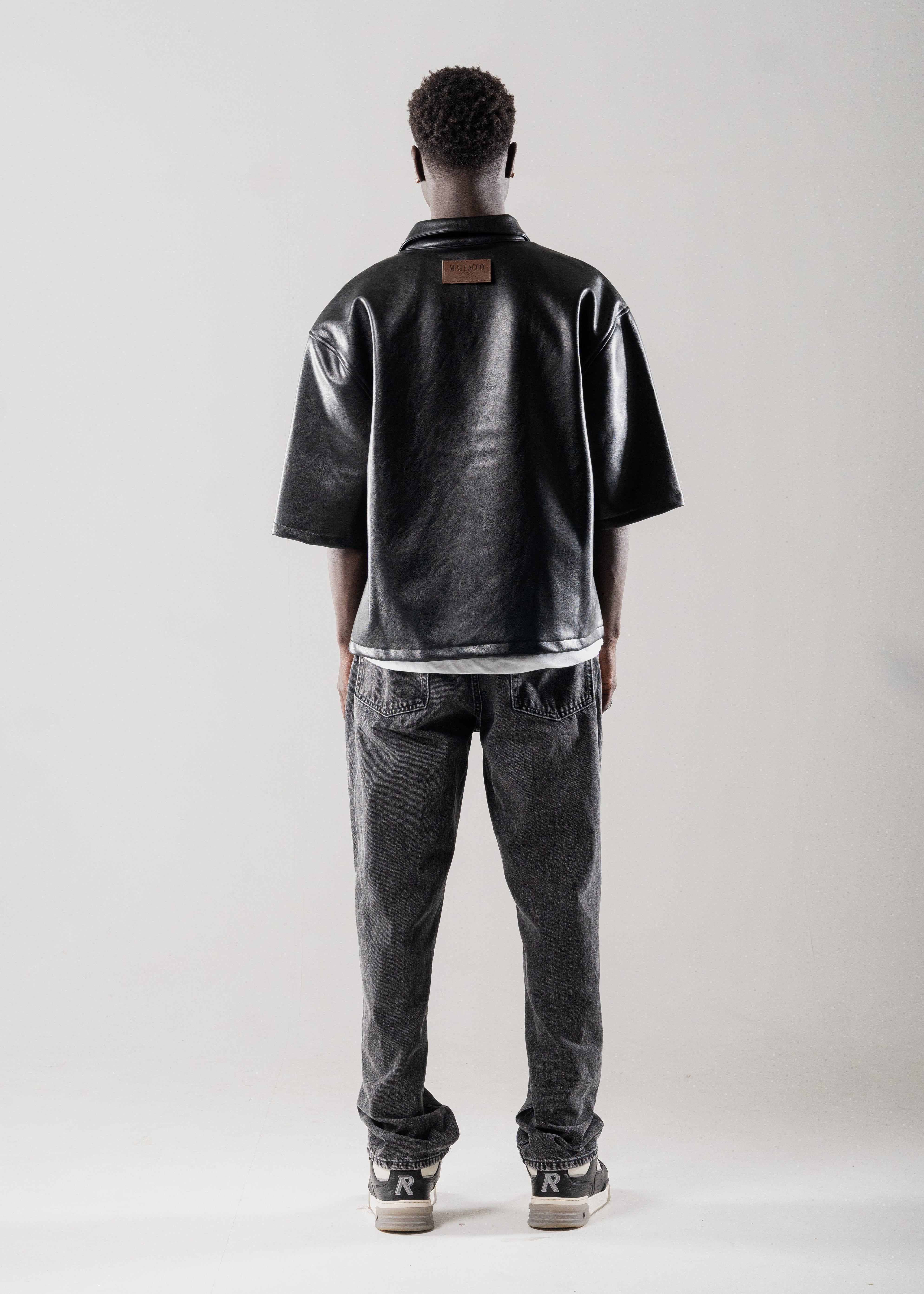Model styled in Mallacco black vegan leather shirt with straight trousers